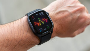 Gros plan sur le poignet d’un homme portant une montre connectée noire affichant une fréquence cardiaque et des données de santé.